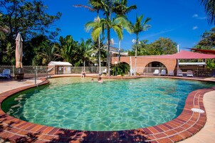 Una piscina al aire libre, sillones reclinables de piscina