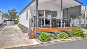 A modern single-story house with a covered porch, a small outdoor seating area, and a visible garage door. - Ingenia Holidays South West Rocks (South West Rocks)
