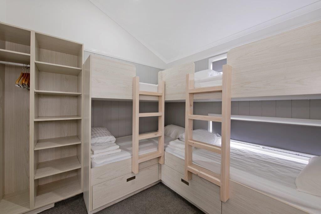 Une chambre avec des lits superposés, une armoire et une fenêtre.