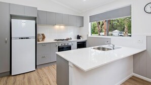 A modern kitchen with grey cabinets, a white countertop, and a window with a view of the outdoors. - Ingenia Holidays South West Rocks (South West Rocks)