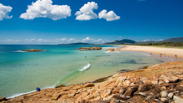 A coastal landscape with clear blue waters, rocky shore, and a sandy beach. - Ingenia Holidays South West Rocks (South West Rocks)