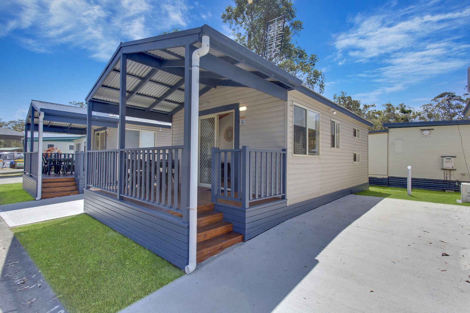A single-story mobile home with a covered porch, a small deck, and a front entrance.