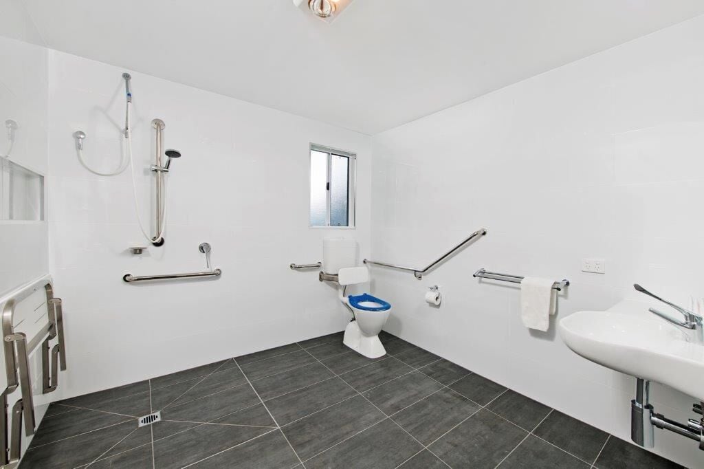 A modern bathroom with a white toilet, a sink, and a shower area.