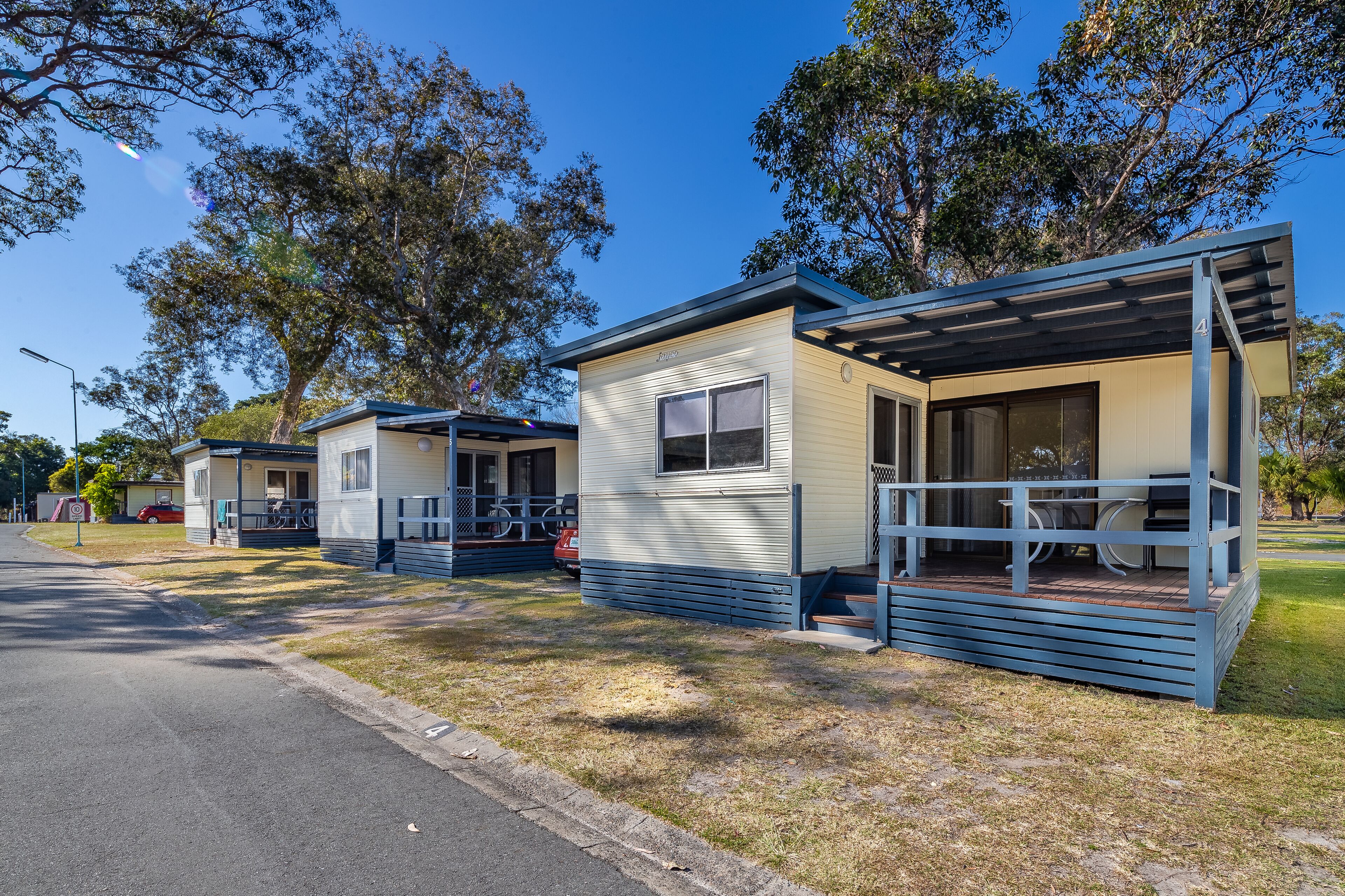 A row of single-story mobile homes with attached porches, each featuring a small deck and outdoor seating.