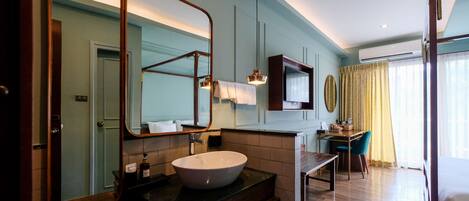 A hotel bathroom with a large mirror, a sink, and a vanity.