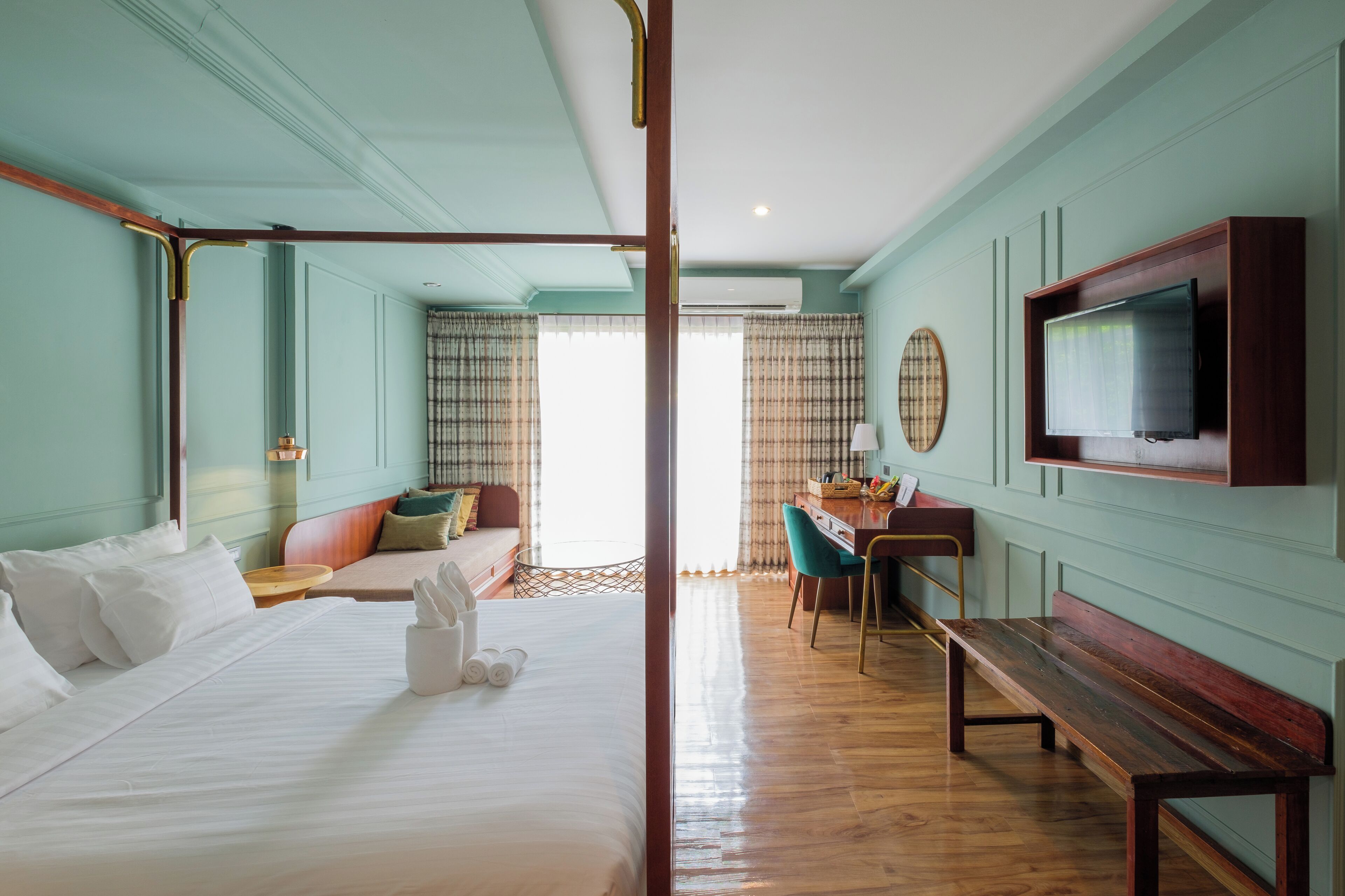 A hotel room with a large bed, a desk, a chair, and a television mounted on the wall.