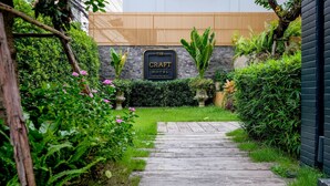 Un camino que lleva a un edificio con un cartel que dice "The Craft Hotel Chiang Mai".