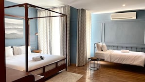 Un dormitorio con una cama con dosel, una cama más pequeña y una mesita de noche con lámpara.