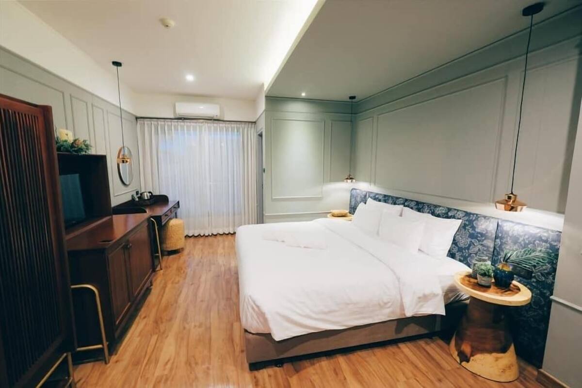 A hotel room with a bed, bedside table, and a desk with a chair.