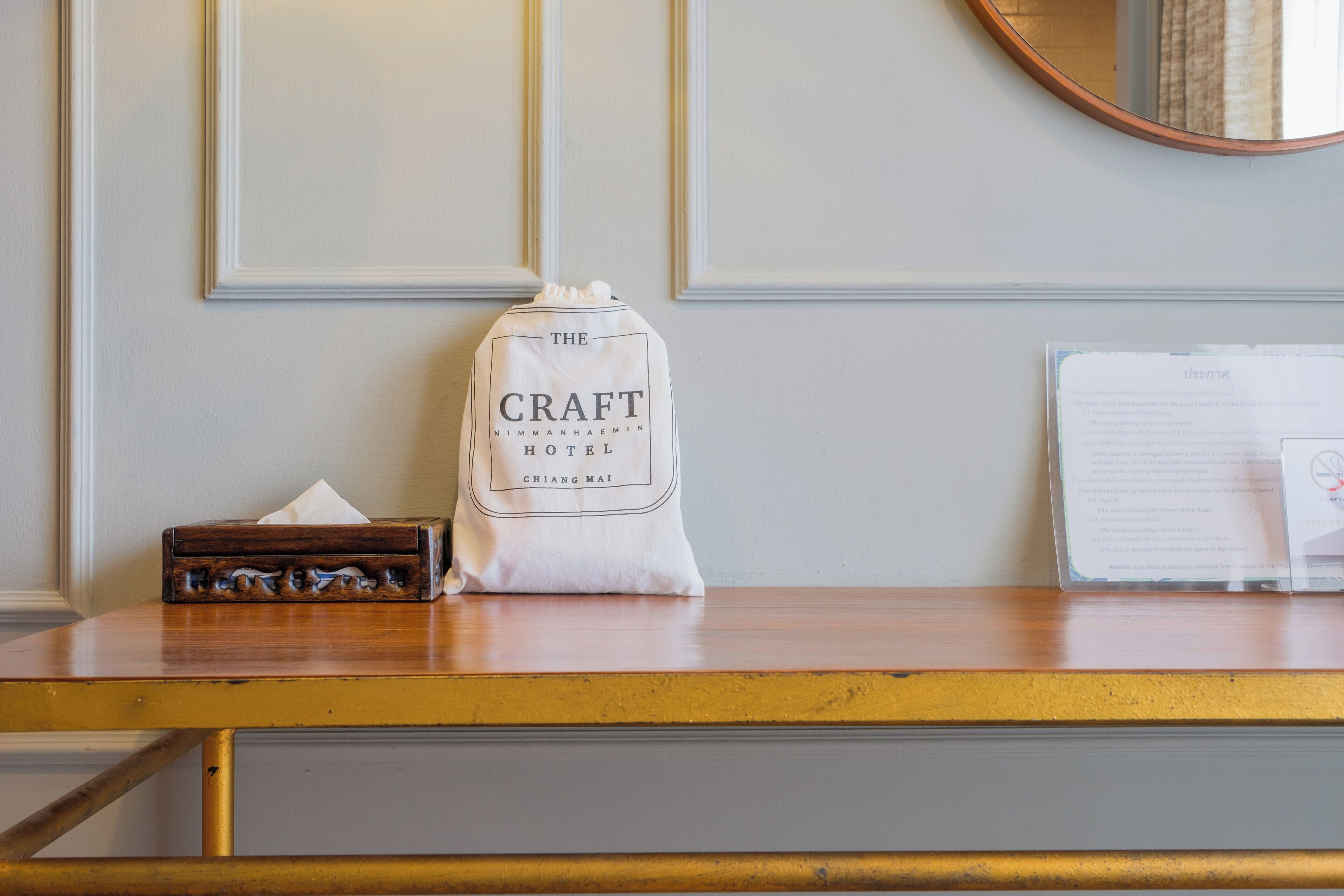 Una mesa de recepción con una bolsa blanca que dice "The Craft Hotel Chiang Mai" y una caja de madera.
