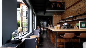 Zona de bar moderna con pared de ladrillo, taburetes y barra donde una persona atiende.
