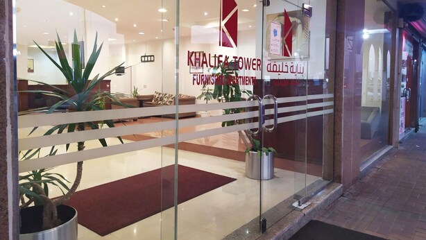 Ein Einrichtungshaus mit Glastüren, einem roten Logo und einem roten Teppich, der zum Eingang führt.