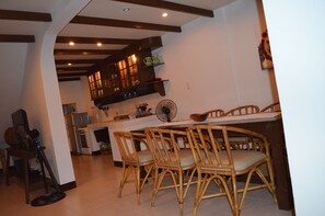 A kitchen with a central island, wooden chairs, and a fan.
