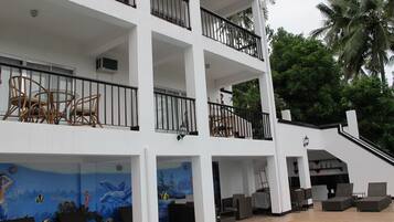 Un hotel de varios pisos con balcones, mobiliario exterior y una zona de piscina.