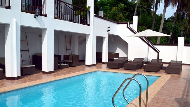 Una piscina con sillas de descanso y una escalera que sube a un nivel superior.