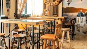 Ein Restaurant mit Holztischen und -stühlen, einer Klimaanlage und einem Wandbild mit einer Küstenansicht.