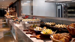 Een buffet met verschillende soorten eten en een keuken op de achtergrond.
