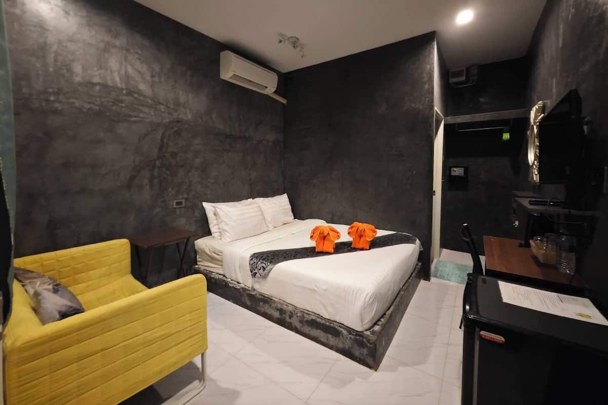 A modern hotel room with a bed, a yellow armchair, and a small desk.