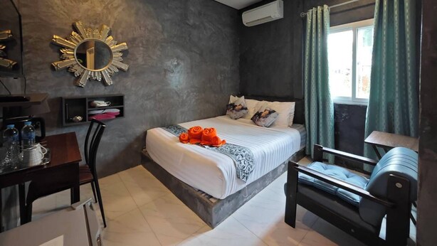 Un dormitorio moderno con cama, escritorio, silla, tocador y ventana con cortinas.