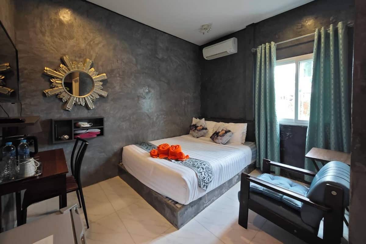 A modern bedroom with a bed, a desk, a chair, a vanity, and a window with curtains.