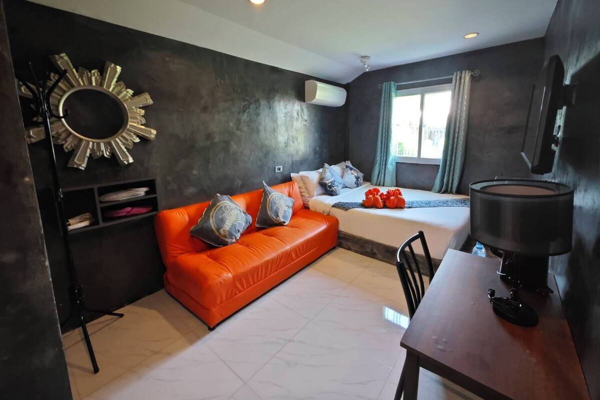 A compact living space with a sofa, a small table, and a bed.