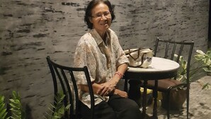 Una persona sentada a una mesa, con un letrero que dice 'La Chambre' al fondo.