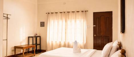 Una habitación de hotel con cama, mesita de noche y perchero.