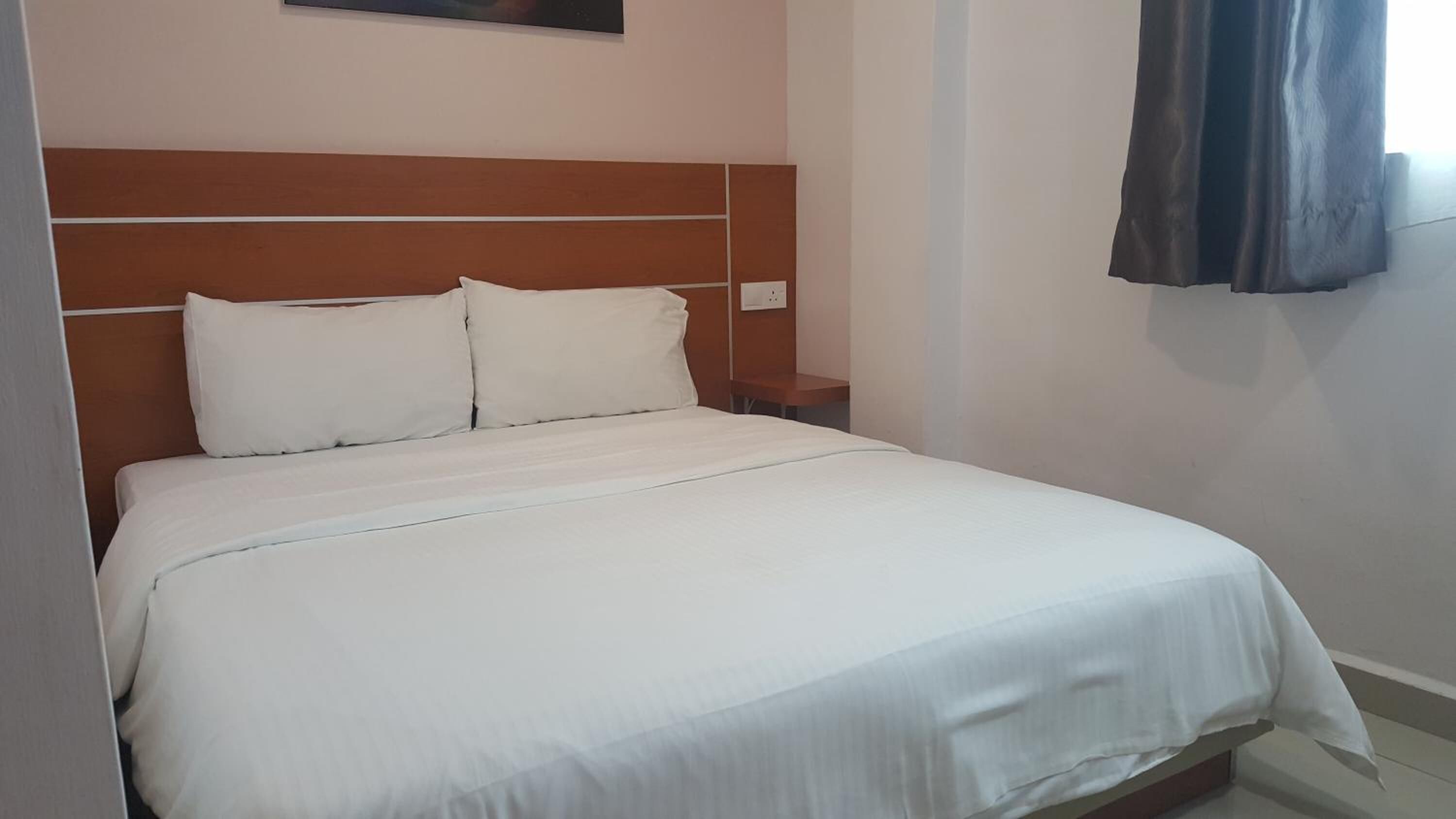 Una cama bien hecha con ropa de cama blanca en una habitación de hotel.