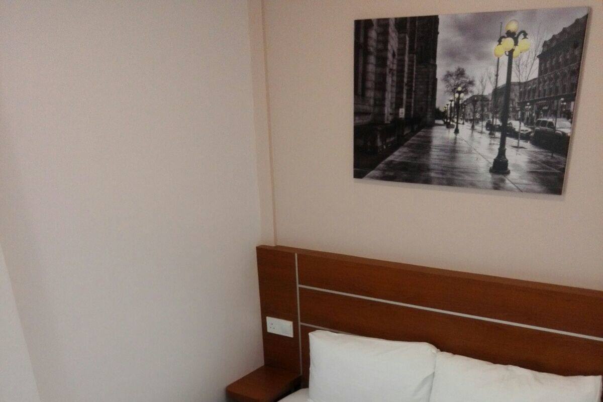 A neatly made bed with white linens in a hotel room.