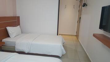 A hotel room with two beds, a TV, and a door leading to a bathroom.