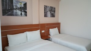 A hotel room with two beds, a wooden headboard, and two black-and-white photographs on the wall. - DOTA Hotel (Alor Setar)