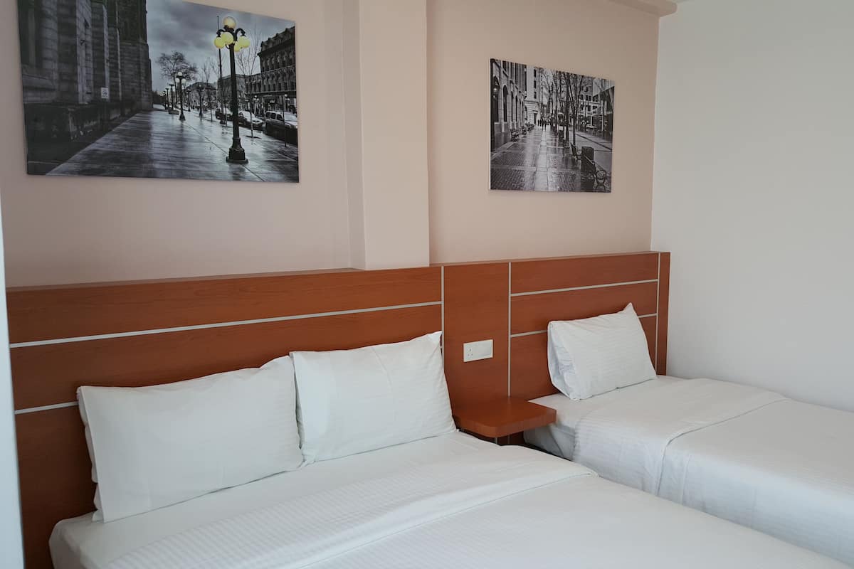 A hotel room with two beds, a wooden headboard, and two black-and-white photographs on the wall.