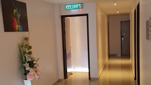 A hotel corridor with a sign for the 'KELUAR' room, a floral arrangement, and a clean, tiled floor. - DOTA Hotel (Alor Setar)
