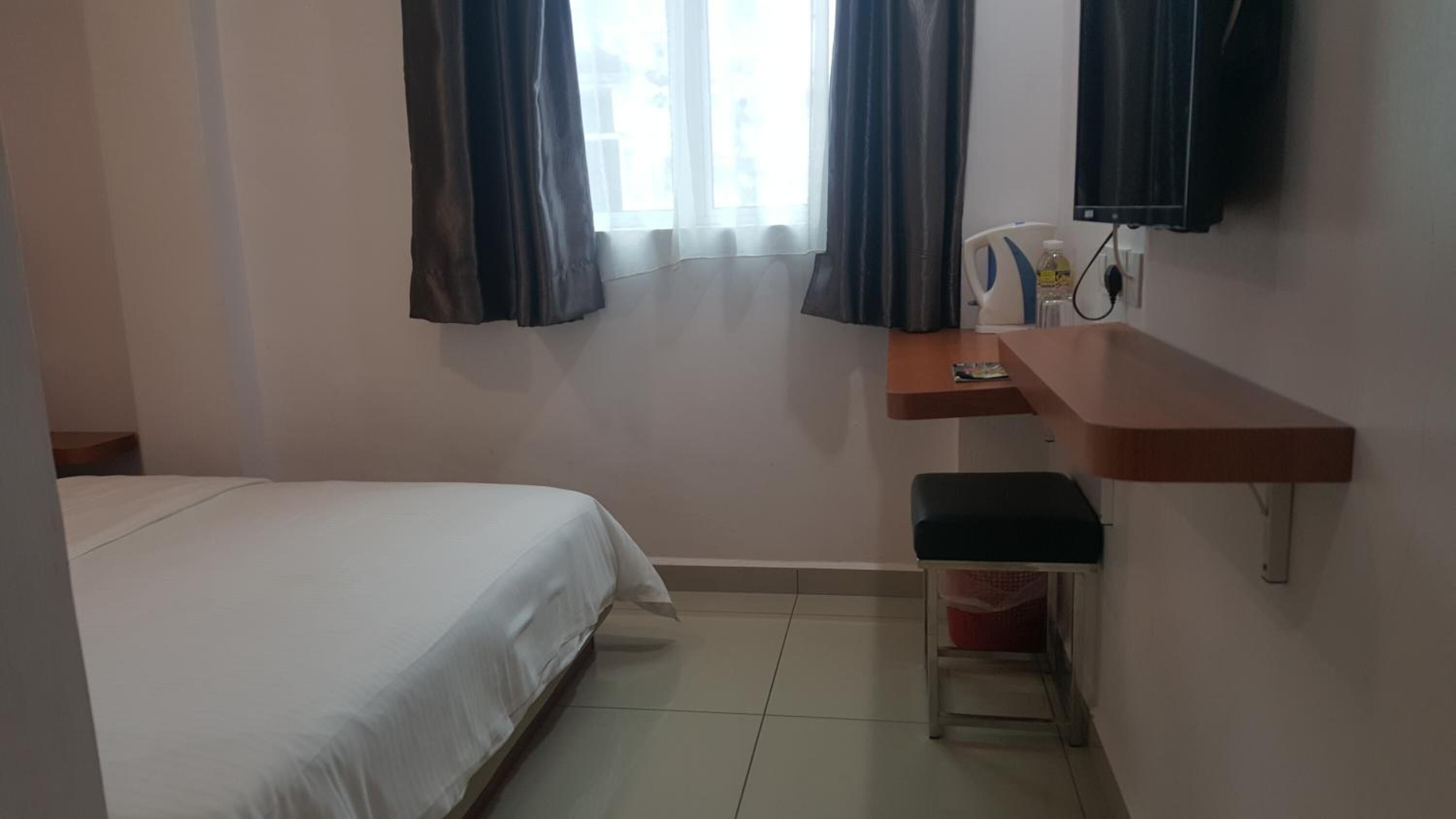 A bedroom with a bed, a desk, a chair, and a window with curtains.