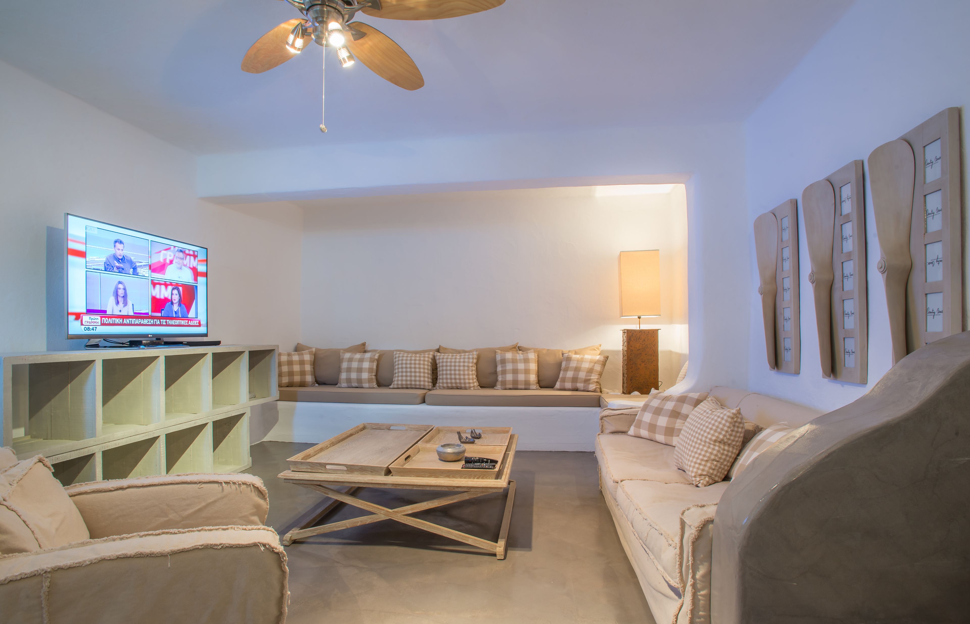 A living room with a television, sofa, coffee table, and decorative wall pieces.