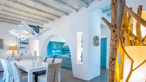 Una cocina moderna con gabinetes azules y una zona de comedor blanca con una mesa y sillas.