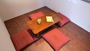 A small dining area with a wooden table and four red cushioned benches. - leaf hostel (Tainan)