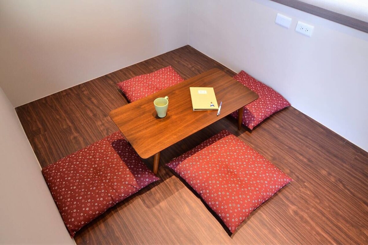 A small dining area with a wooden table and four red cushioned benches.