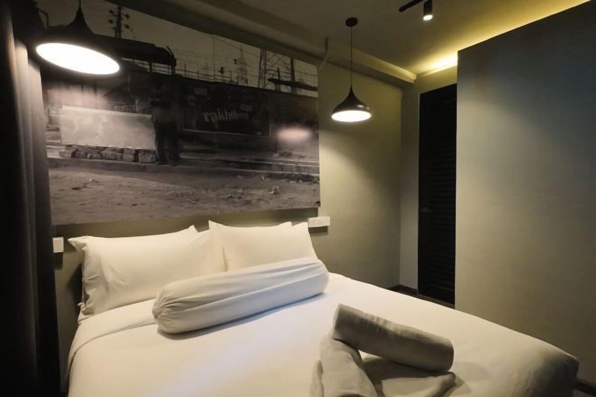 Una habitación de hotel con una cama, un cartel grande en la pared y una lámpara colgante.