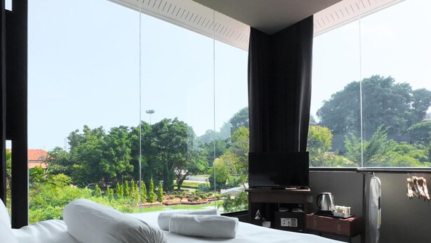 A hotel room with a large bed, a TV, and a view of a park. - Rucksack Inn Premium Melaka (Malacca City)