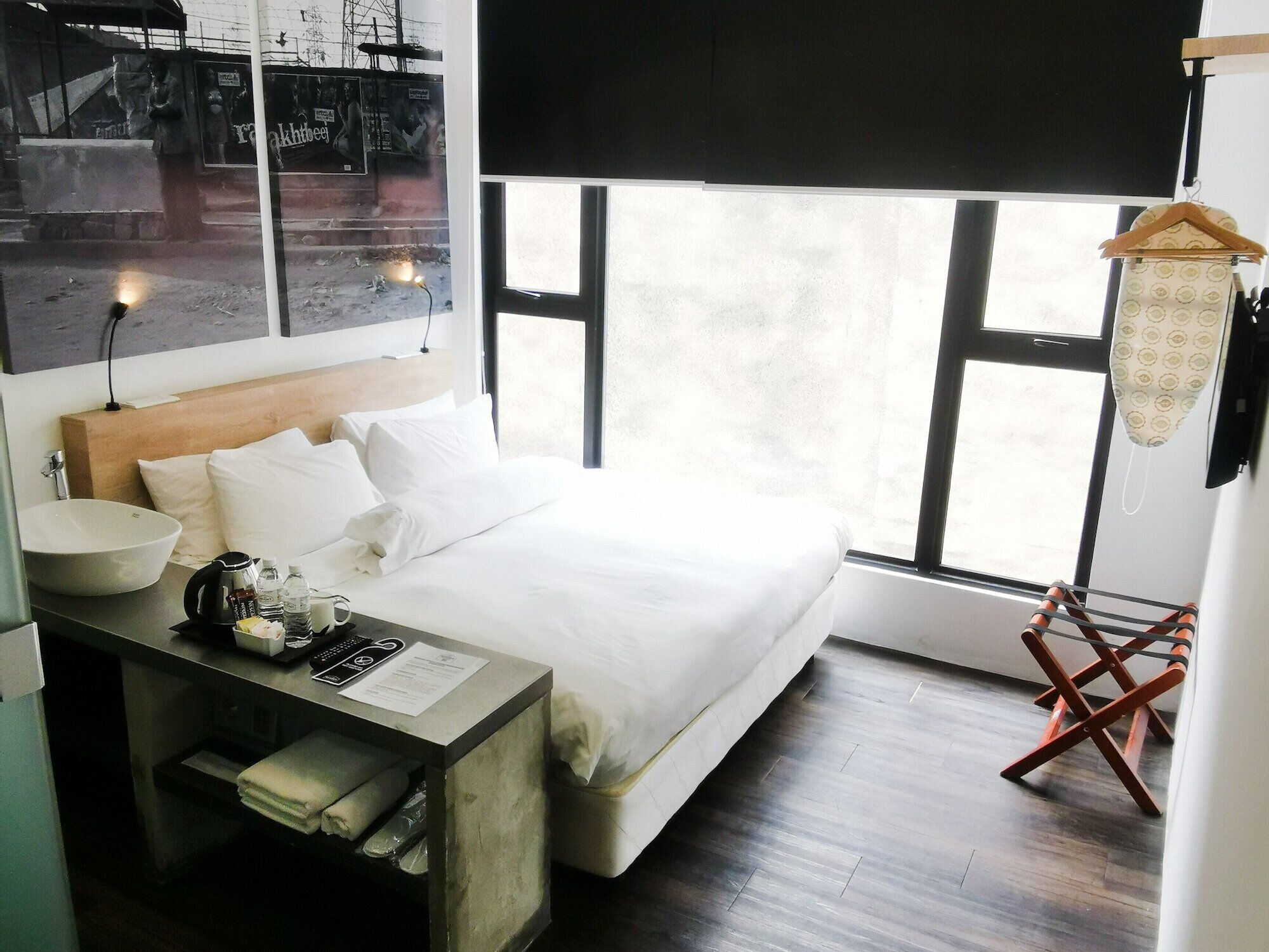 A hotel room with a bed, bedside table, lamp, and a window with a view.