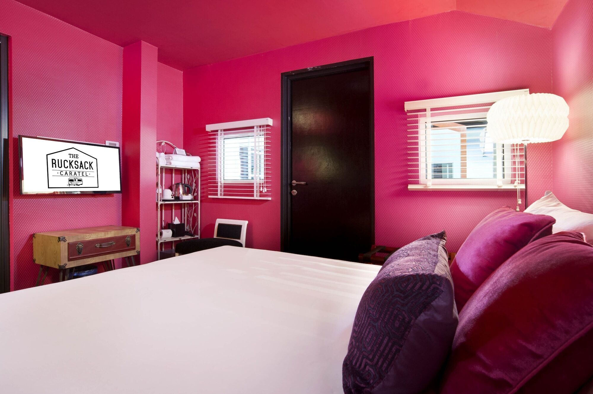 A room with a bed, a desk, a wardrobe, and a window with blinds.