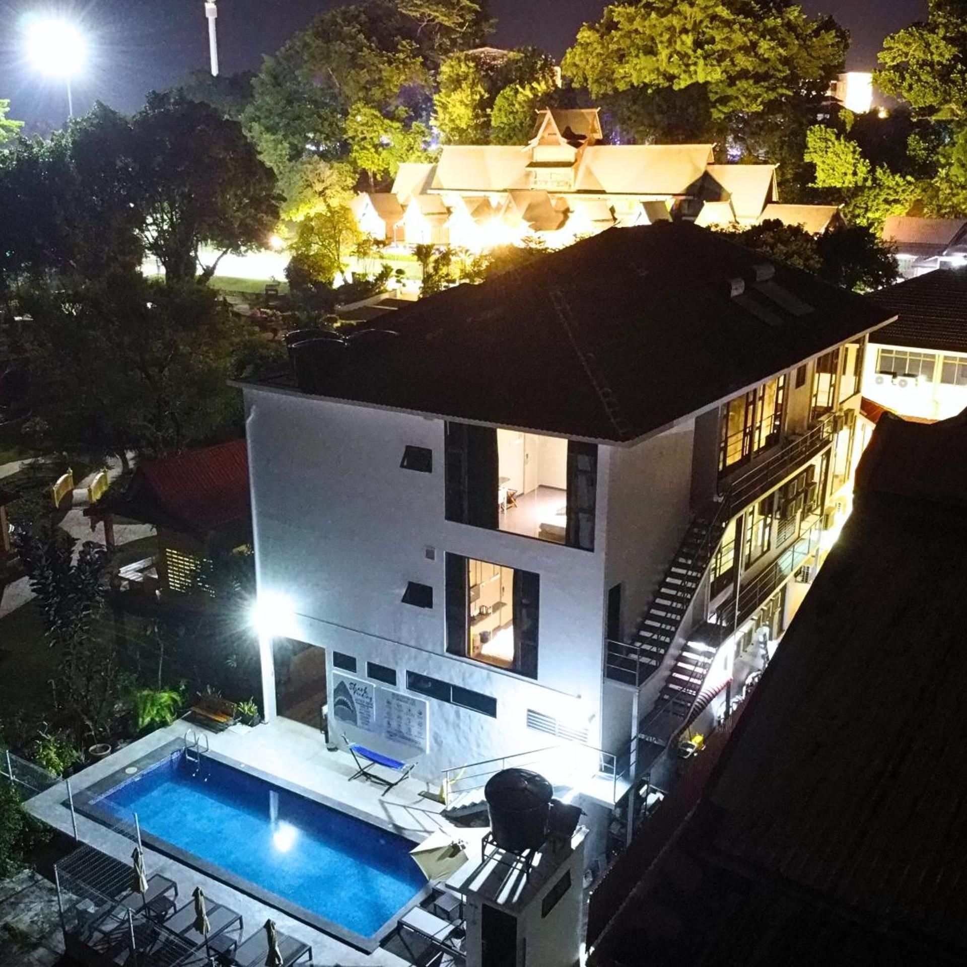 Un edificio de varios pisos con piscina, mobiliario exterior y una escalera que lleva a un nivel superior.