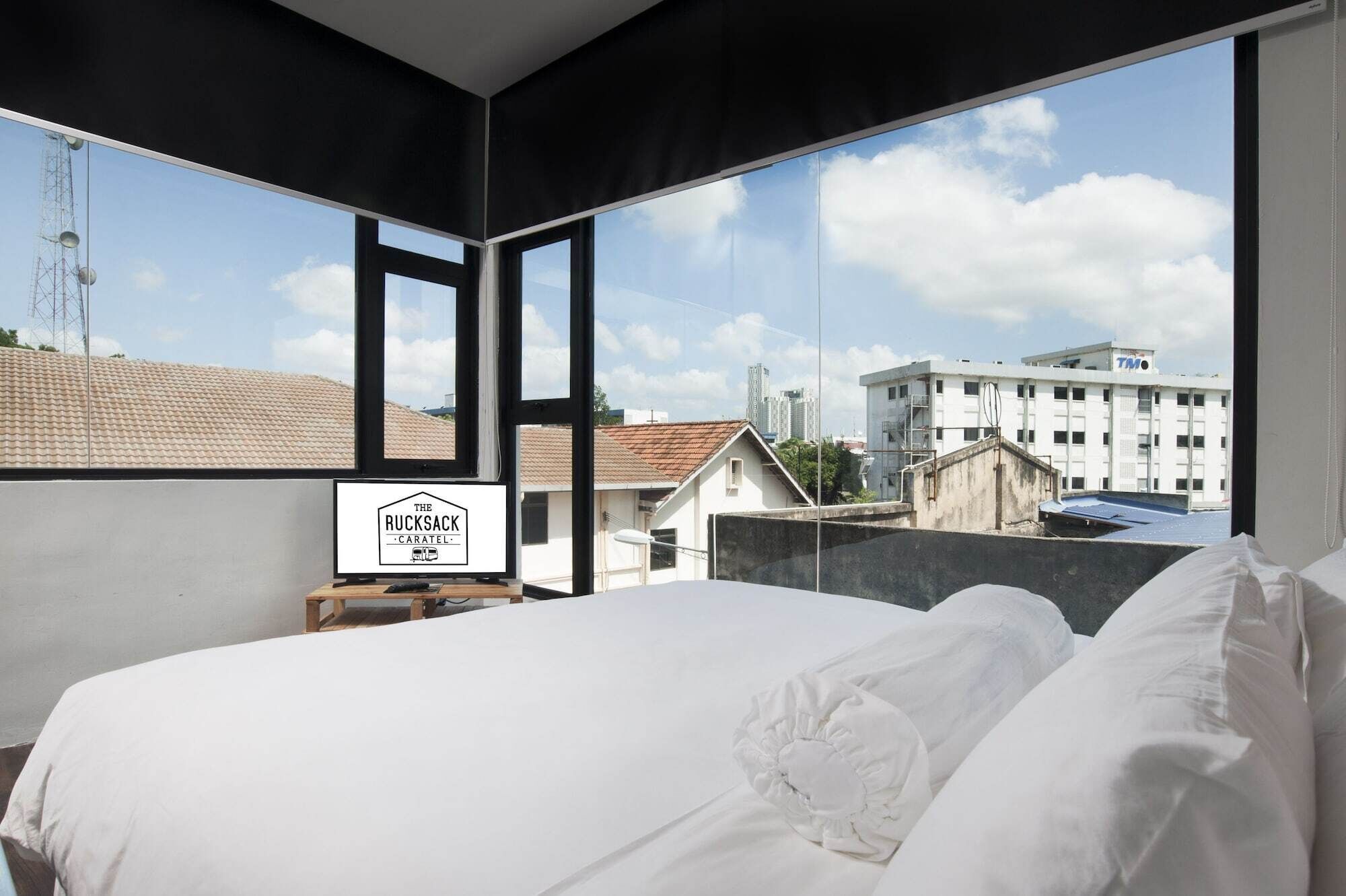 Habitación de hotel con una cama grande, vista a la ciudad y un letrero que dice 'The Rucksack Caratel'.