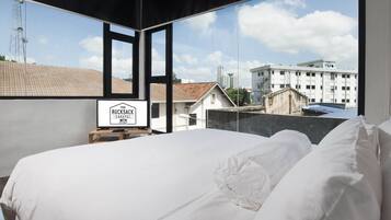 Habitación de hotel con una cama grande, vista a la ciudad y un letrero que dice 'The Rucksack Caratel'.