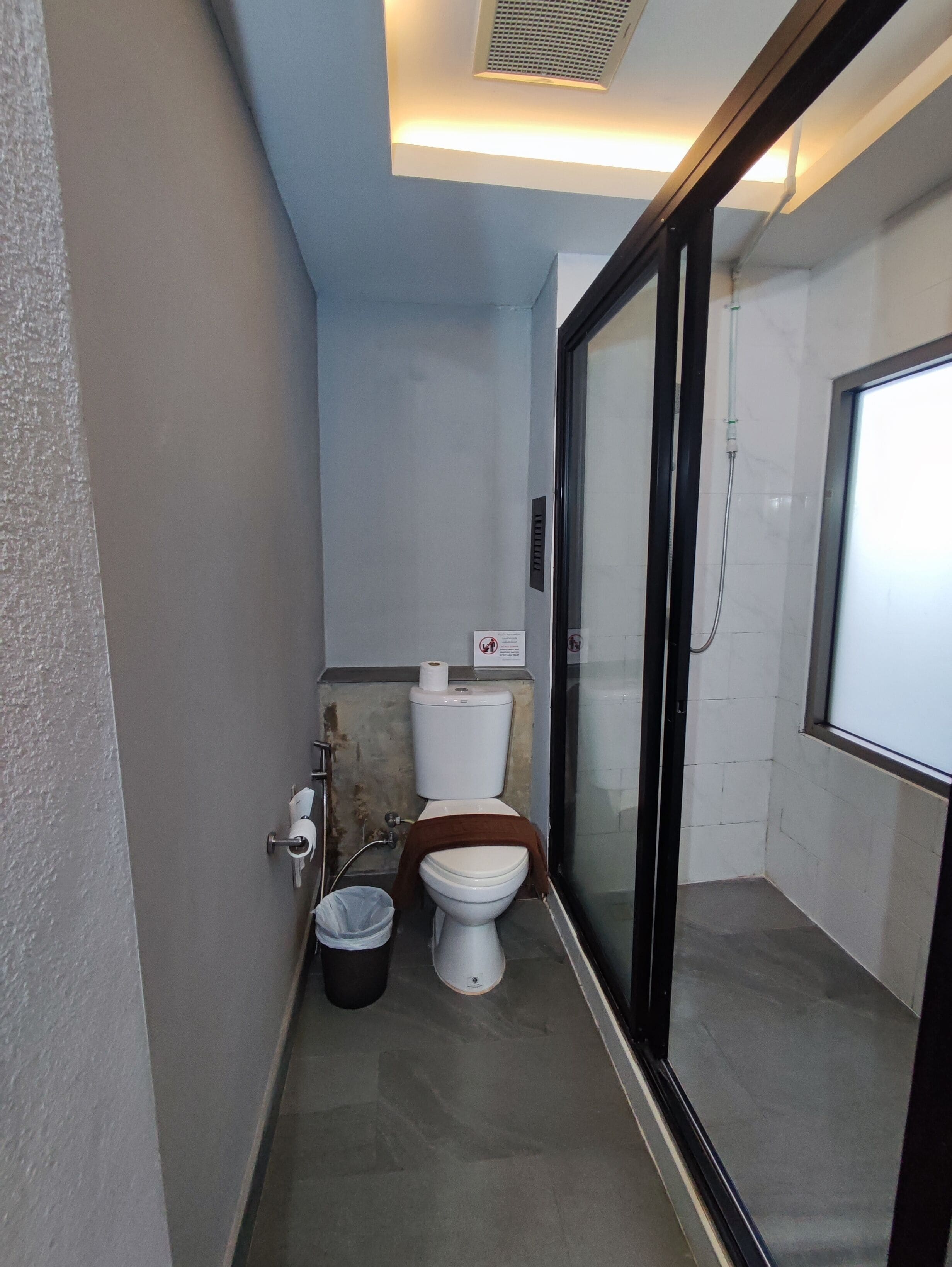 Een kleine badkamer met toilet, prullenbak en douche.