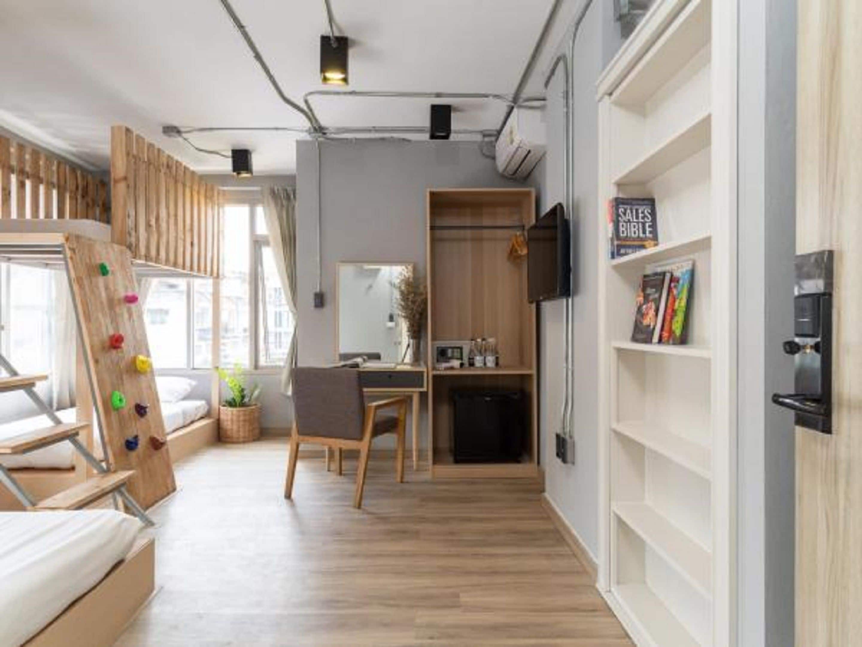 A modern, well-lit room with a wooden climbing wall, a desk, and a bookshelf with a 'SALE BIBLE' sign.
