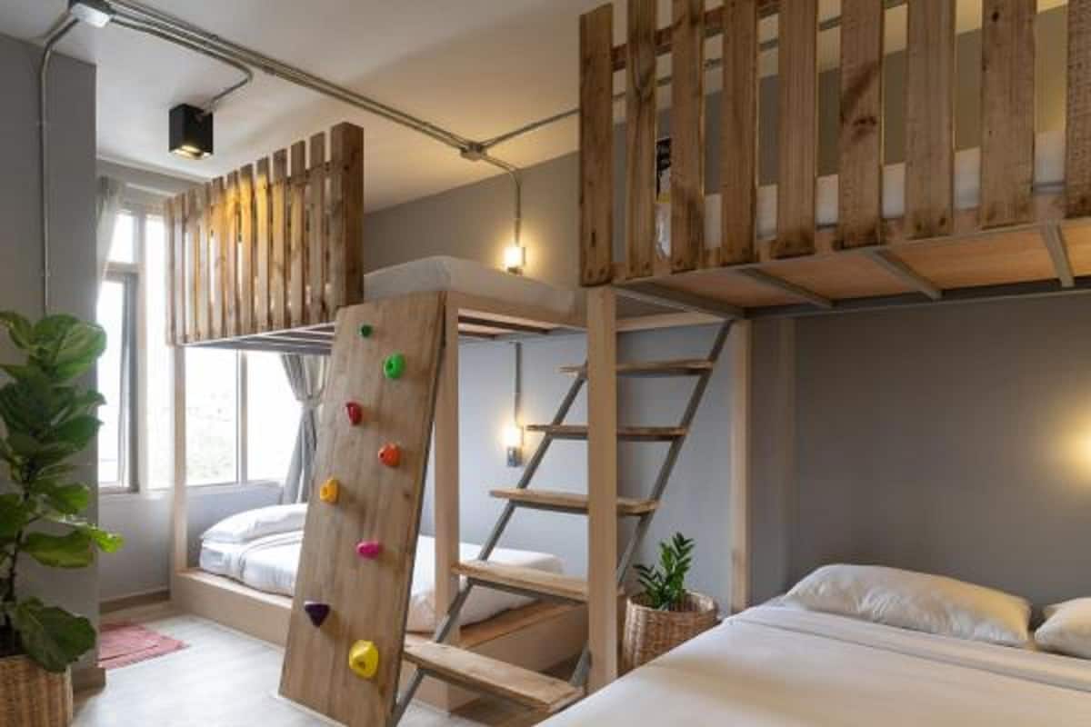 Un lit superposé avec un mur d’escalade, une table de chevet et une fenêtre laissant entrer la lumière naturelle.