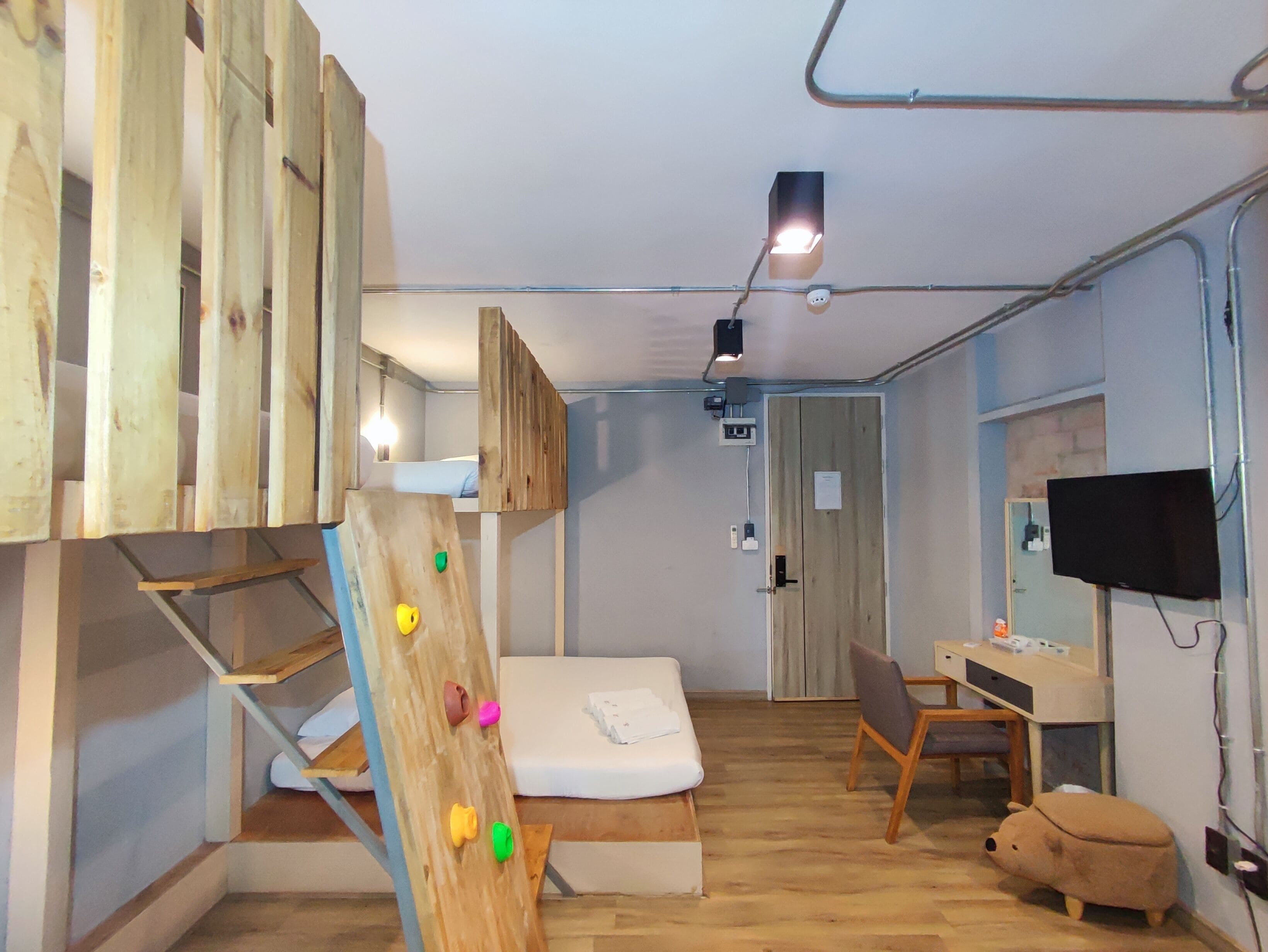A room with bunk beds, a desk, a chair, a television, and a small sofa.