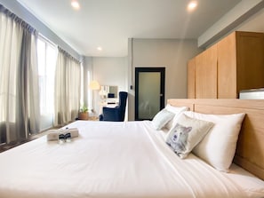 Une chambre d’hôtel avec un grand lit, un bureau, une chaise et une armoire.